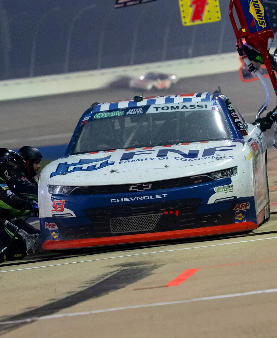 Pit crew refueling a race car during a night race