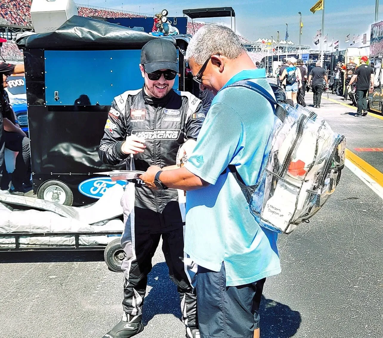 Driver signing an autograph for a fan in the pit area
